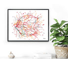 Framed eye anatomy print on a white wall, next to a plant and decorative items.